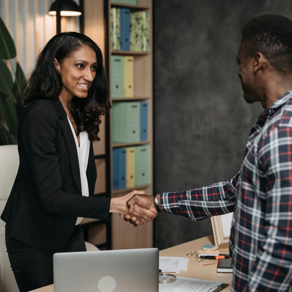 Two professionals shake hands in a modern office, symbolizing a successful agreement.